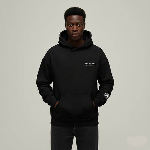 Person wearing a black hoodie with a logo on a beige background