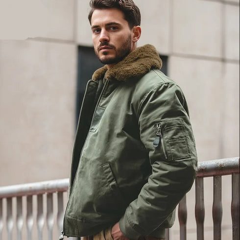 Man wearing a green jacket with fur collar standing outdoors.