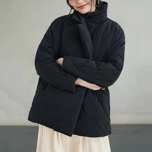Person wearing a black coat with a neutral background