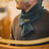 Man wearing a textured sweater and green scarf with a blurred background