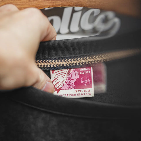 Hand holding a black bag with a visible brand label featuring a red and white design.