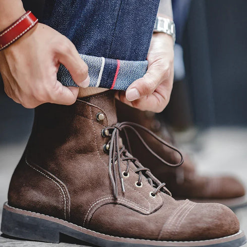 Person adjusting a brown boot with a close-up of the foot and hand.