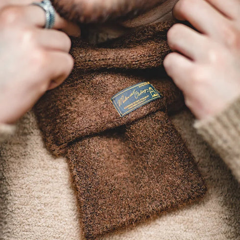 Brown fabric with a label being held by hands, close-up view.