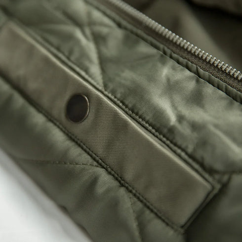 Close-up of a green quilted jacket with a zipper and button detail.