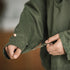 Person wearing a green jacket holding a knife with a blurred background
