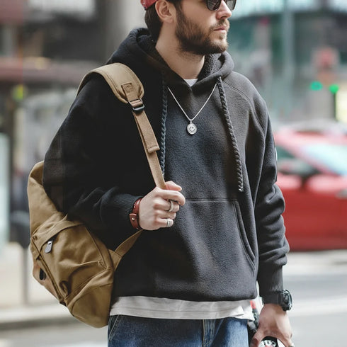 Man wearing a black hoodie with a brown backpack on a city street