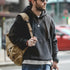 Man wearing a black hoodie with a brown backpack on a city street