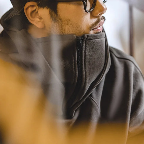Close-up of a person wearing a dark gray hoodie with a blurred background