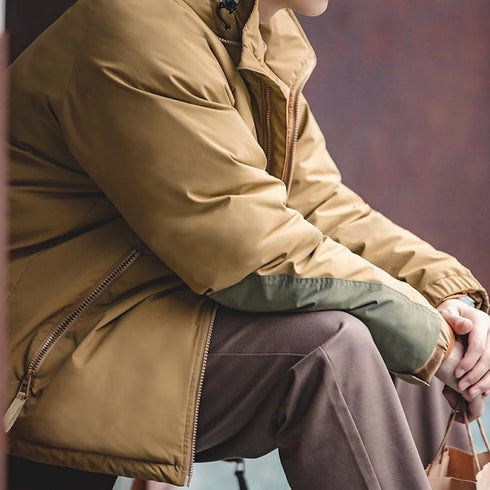 Person wearing a beige coat sitting with a blurred background