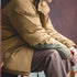 Person wearing a beige coat sitting with a blurred background