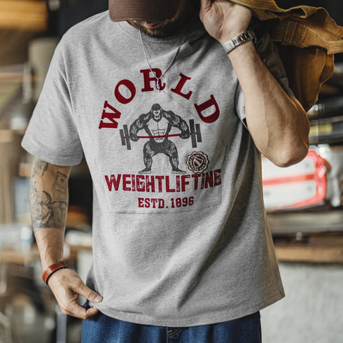 Person wearing a gray t-shirt with world weightlifting graphic design.
