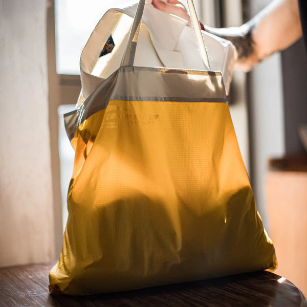 Yellow tote bag with gray accents on a wooden surface