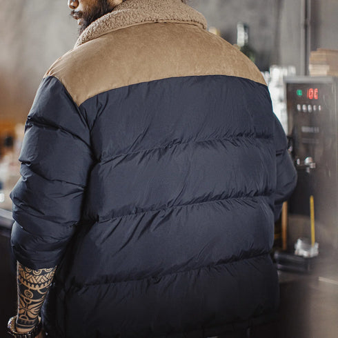 Person wearing a navy blue puffer jacket with a brown collar in an indoor setting.