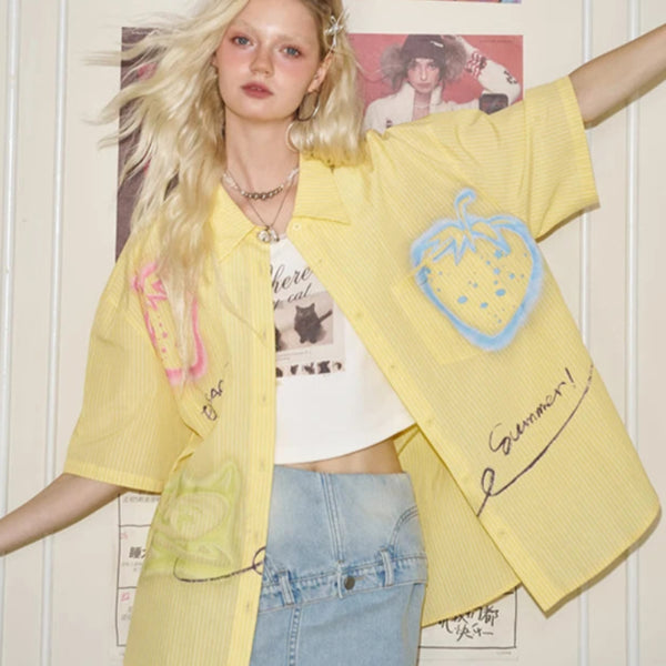 Person wearing a yellow oversized shirt with graphic designs in a casual setting