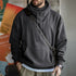 Person wearing a gray hoodie with a shoulder bag against a blurred background