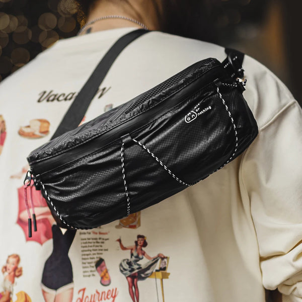 Black leather waist bag worn by a person with a graphic design on their clothing.