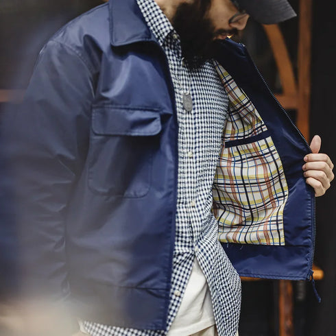 Person wearing a blue jacket over a checkered shirt with a blurred background