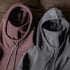 Two hoodies, one brown and one gray, on a wooden surface.