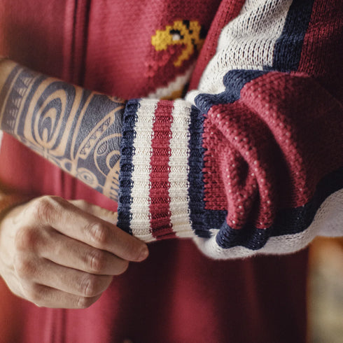 Close-up of a person wearing a red sweater with a patterned sleeve and matching gloves.