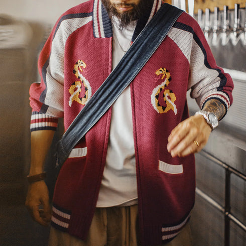 Person wearing a red varsity jacket with anchor designs in a casual setting