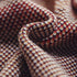Close-up of textured fabric with a pattern of red, yellow, and brown.
