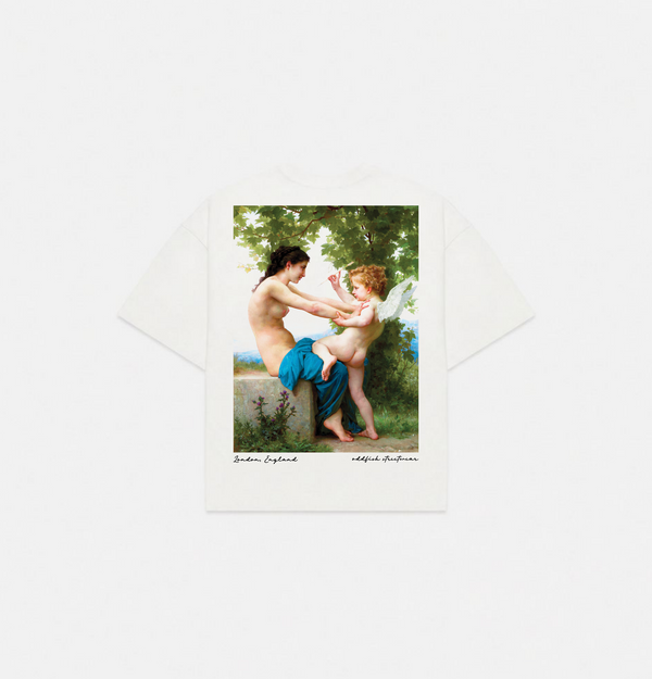 A white short-sleeve T-shirt laid flat on a light gray background, featuring a large vintage-style classical art print on the front depicting a nude adult and child with a winged figure in a green outdoor scene. Small text appears below the print.