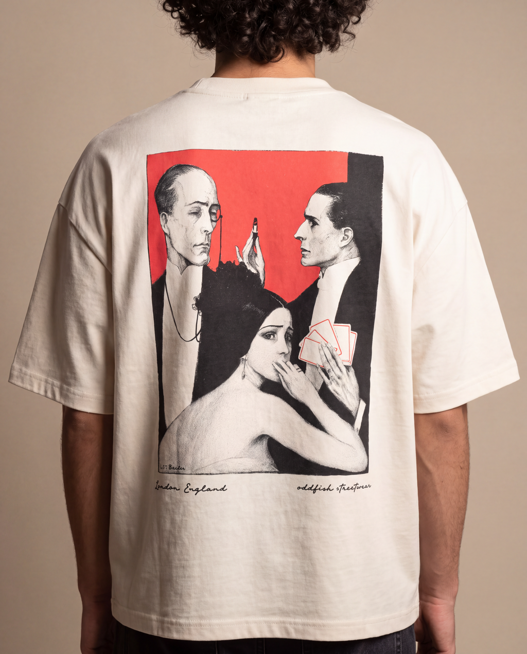 A person shown from the back wearing an oversized off-white graphic T-shirt. The shirt features a large rectangular print on the back with a red background and black-and-white illustrated figures, photographed against a plain beige studio backdrop.